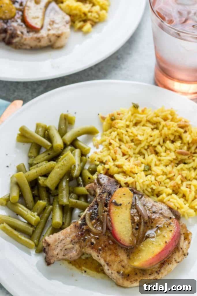 Beautifully pan-seared Peach and Dijon Pork Chops garnished with fresh thyme and peaches.
