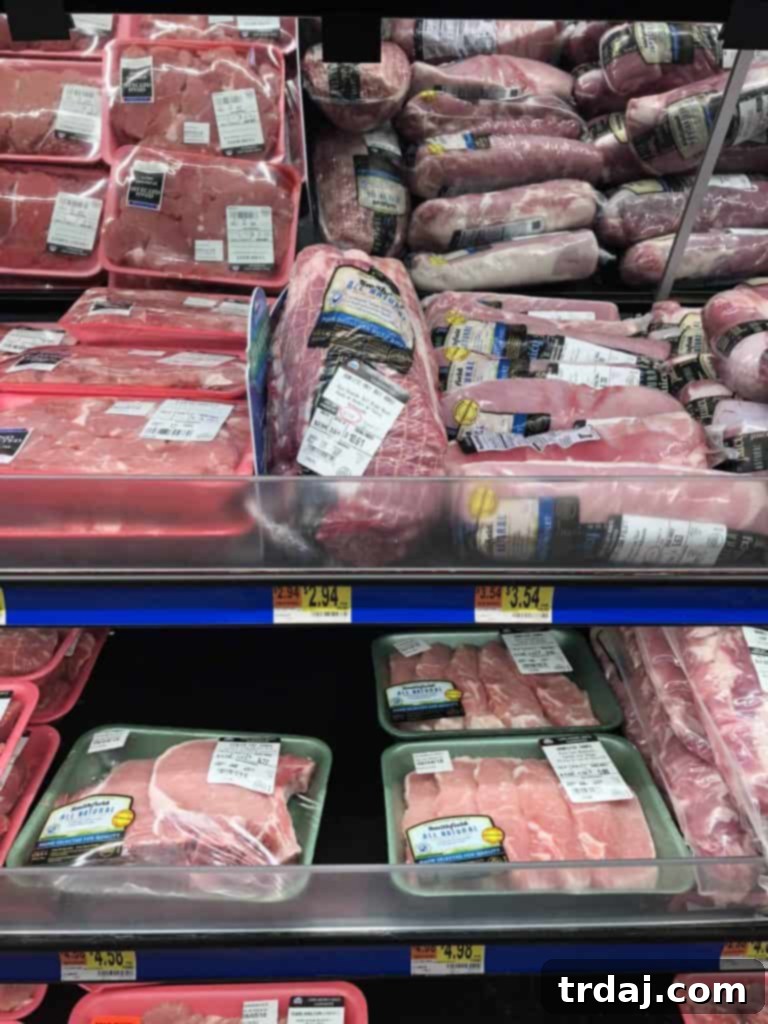 Shopping cart filled with groceries, including fresh produce and meat, in a Walmart aisle.
