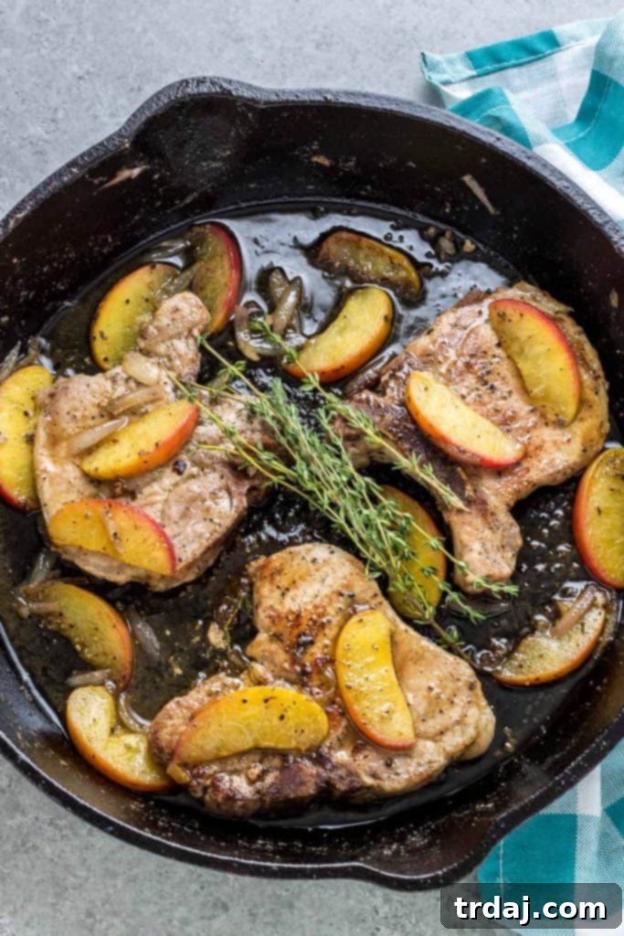 Close-up of Peach and Dijon Pork Chops in a cast iron skillet with the savory-sweet pan sauce.