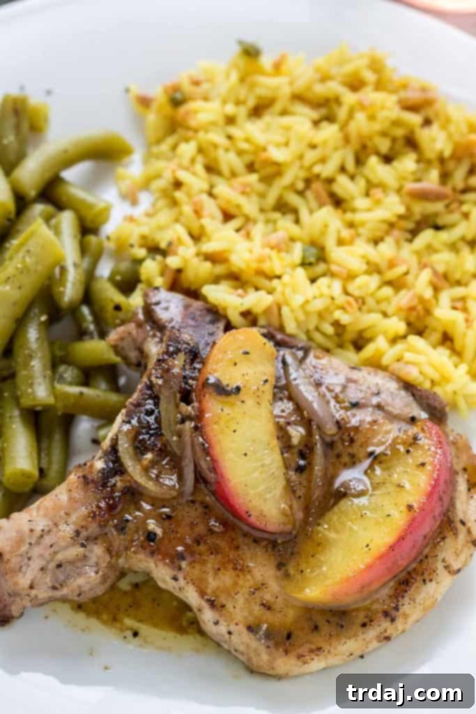 Plated Peach and Dijon Pork Chops served with green beans and rice pilaf for a complete meal.