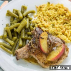 A finished plate of Peach and Dijon Pork Chops with fresh peaches and herbs.