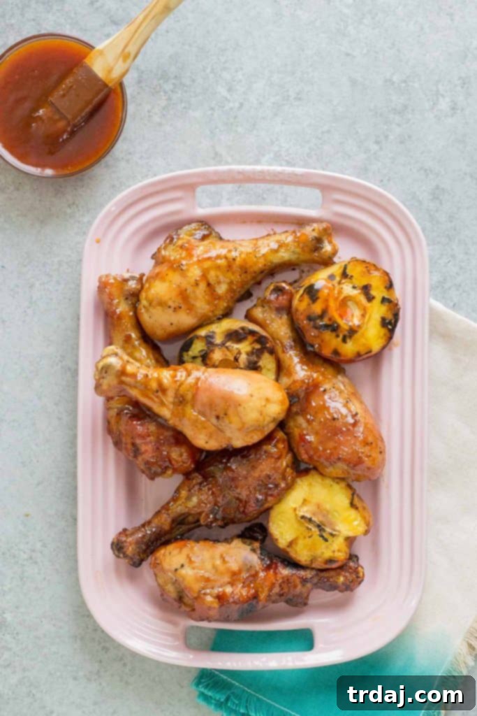 Close-up of BBQ Peach Ginger Glazed Chicken Legs on the grill, showing the caramelized glaze and grill marks.