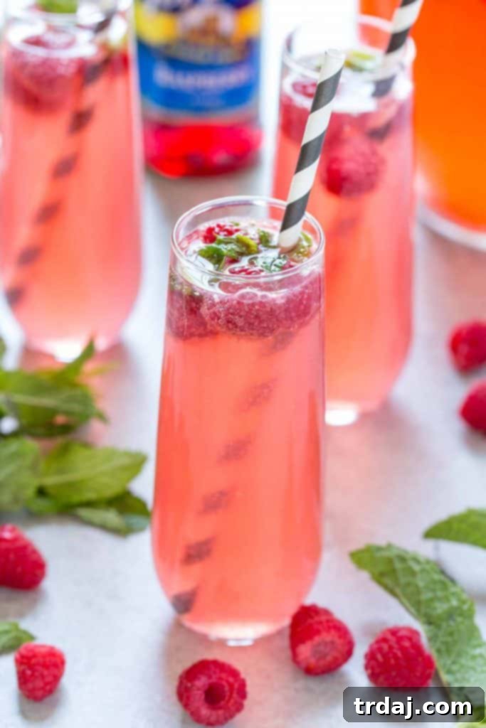 Skinny Raspberry Coconut Mojitos - A vibrant pink cocktail with fresh raspberries and mint garnish