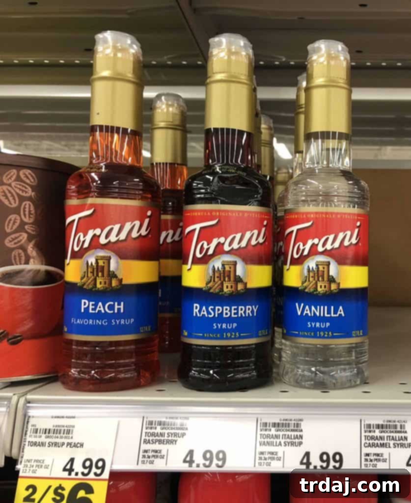 Skinny Raspberry Coconut Mojitos with Sugar Free Raspberry Torani Syrup - A bottle of Torani syrup next to a glass of mojito