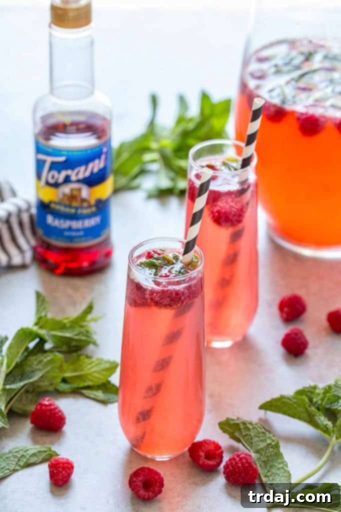 Skinny Raspberry Coconut Mojitos - A close-up of the cocktail glass with raspberries and mint