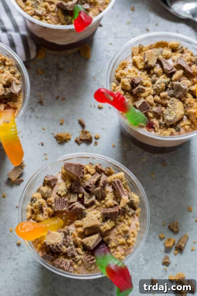 Individual Peanut Butter Dirt Cups arranged on a tray, topped with candy and gummy worms