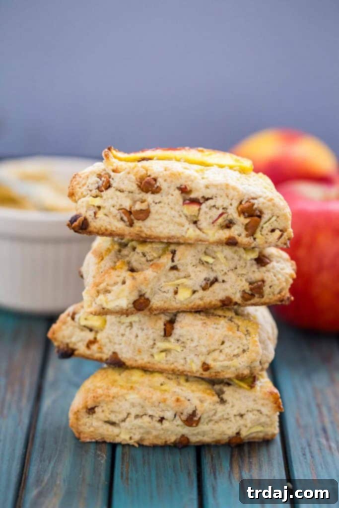 Experience the warmth of Fall with these moist Apple Cinnamon Scones, featuring Envy apples and cinnamon chips, perfectly complemented by homemade Maple Butter. Perfectly baked Apple Cinnamon Scones with Maple Butter drizzle on a cooling rack