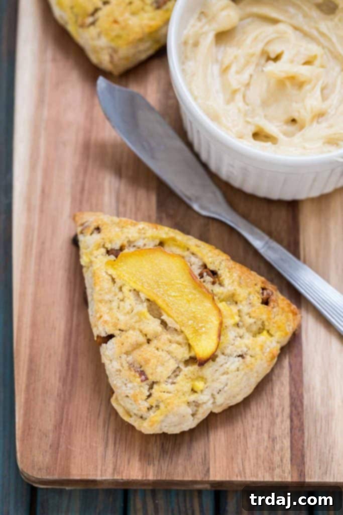 Freshly baked Apple Cinnamon Scones served with creamy Maple Butter, an ideal Fall treat to share or savor. A stack of warm Apple Cinnamon Scones with a small bowl of Maple Butter beside them, ready to be enjoyed