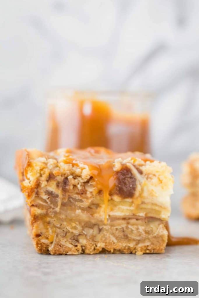 Close-up of a Caramel Apple Cheesecake Bar showing the distinct layers of crust, apple, cheesecake, and crumble.