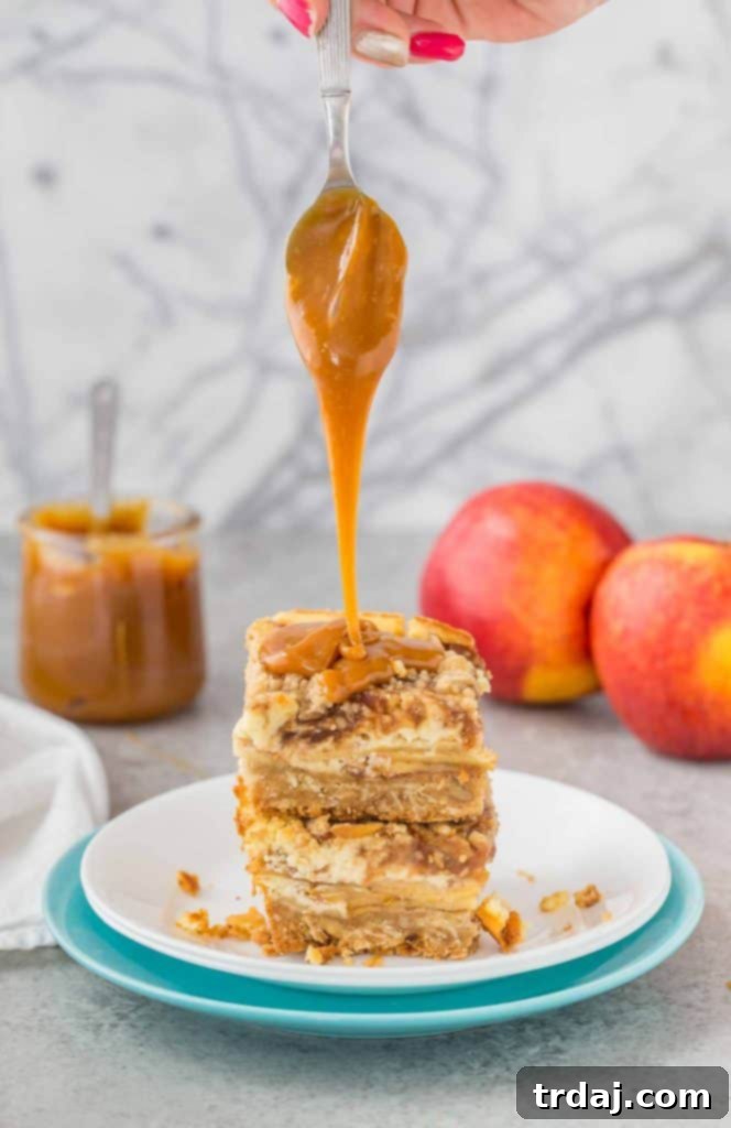 A generous slice of Caramel Apple Cheesecake Bar revealing its intricate layers and delicious caramel drizzle.