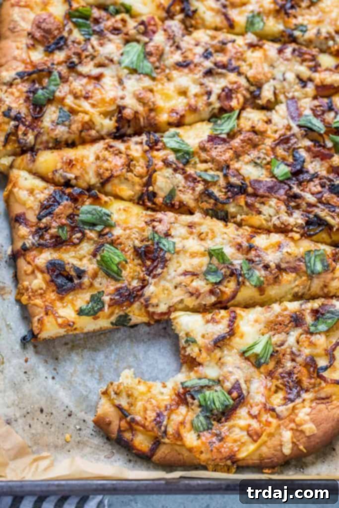A slice of Apple, Bacon and Caramelized Onion Pizza being lifted from the pan, showing the gooey cheese and crispy crust.