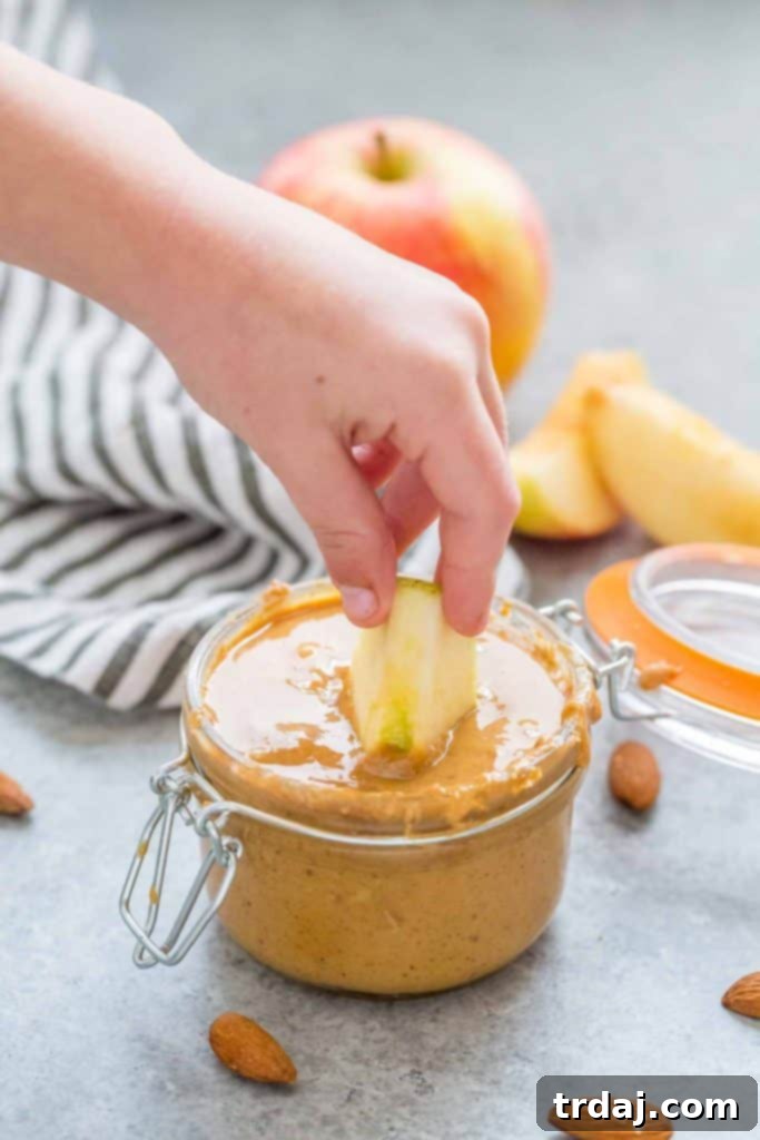 Aromatic spices combine with almonds to create a delicious Apple Chai Almond Butter that's perfectly spreadable on anything from apples to bread and everything in between! A jar of Apple Chai Almond Butter with chai spices in the background