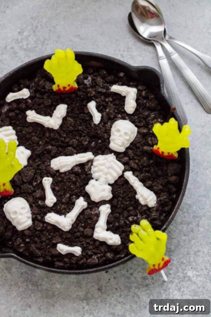 Rich and decadent skillet brownies get topped with chocolate skeletons, gummy zombie hands and 'dirt' to make spooky and delicious Halloween Graveyard Brownies! Family enjoying Halloween Graveyard Skillet Brownies with spooky toppings
