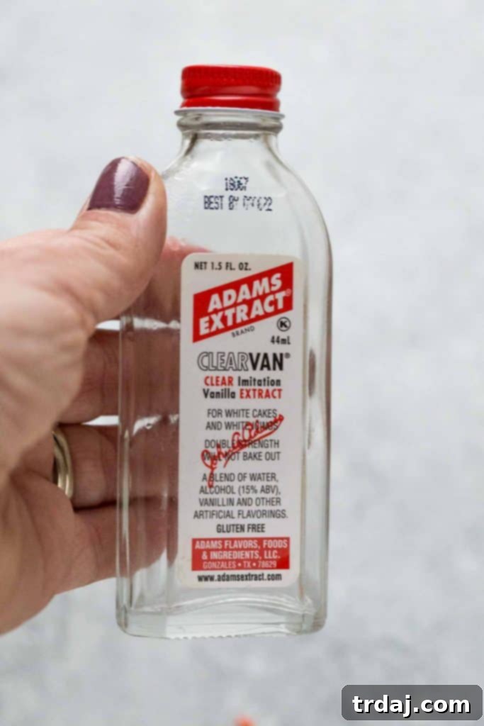 Empty bottle of vanilla extract next to a batch of freshly baked cupcakes, highlighting the importance of quality ingredients