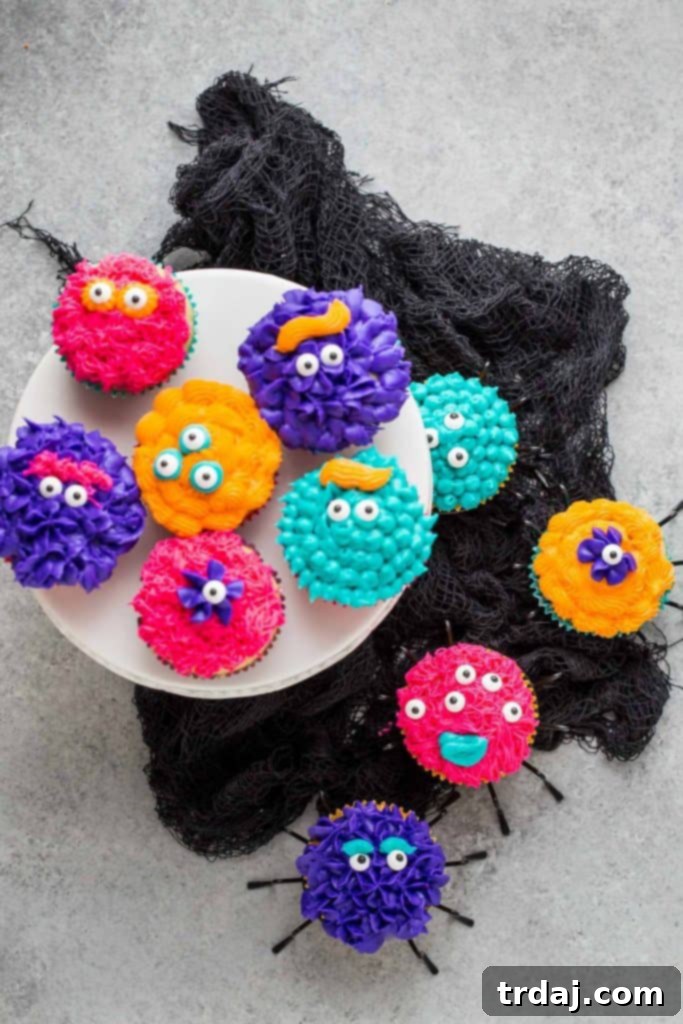 A festive display of Monster Piñata Cupcakes ready for a Halloween party, showcasing various colorful designs