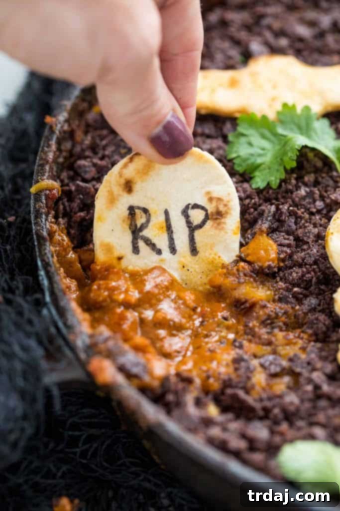 Graveyard Chorizo Dip is full of chorizo, beans, RO*TEL® and cheese. Topped with crushed chips to look like dirt and served with homemade Halloween tortilla chips, it's perfect for all those spooky parties! Graveyard Chorizo Dip