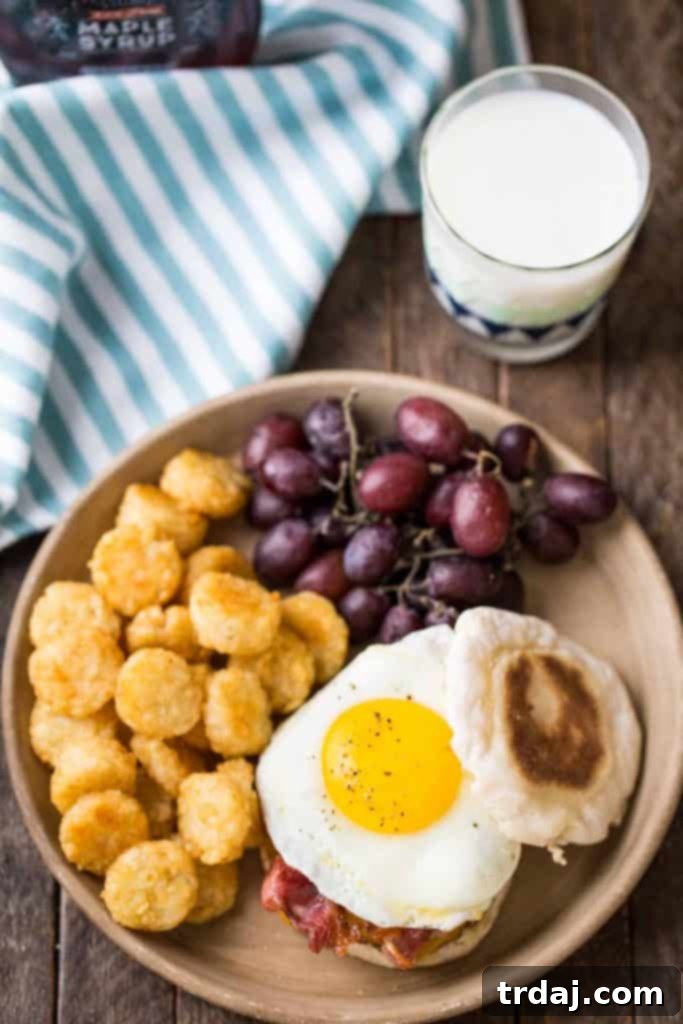The Ultimate Breakfast Burger ingredients laid out: English muffins, sausage patties, cheese, bacon, egg, and maple syrup