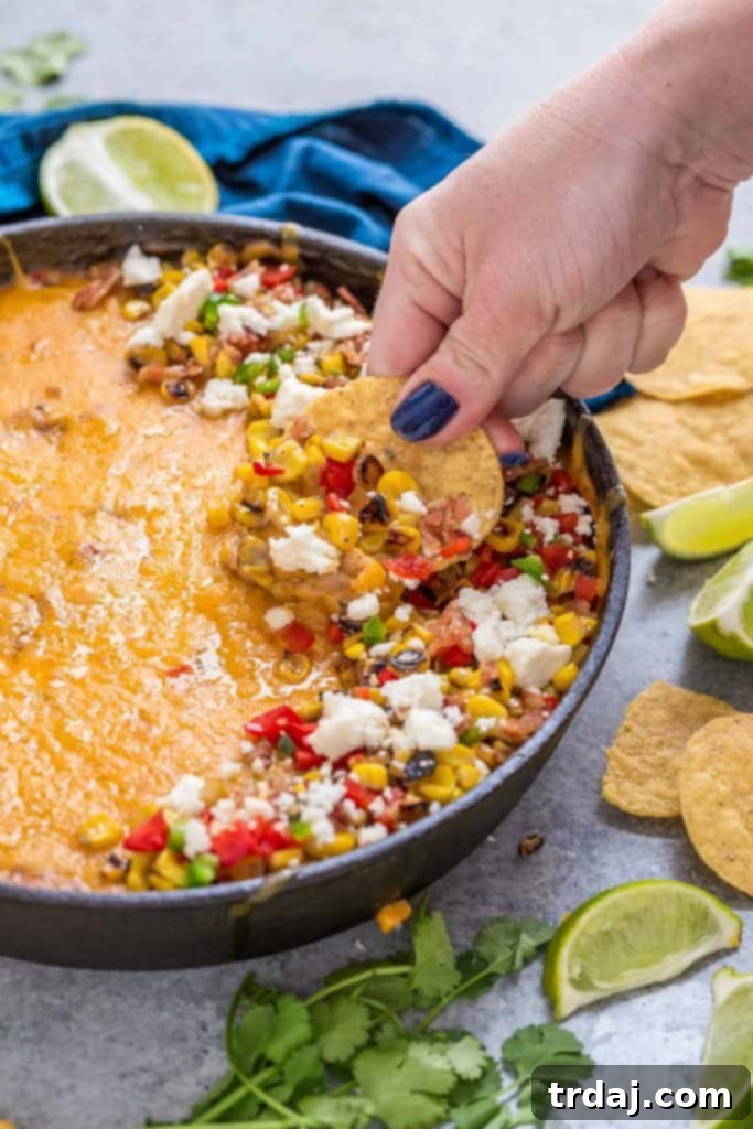 A generous serving of Mexican Street Corn Queso, ready to be enjoyed with tortilla chips.