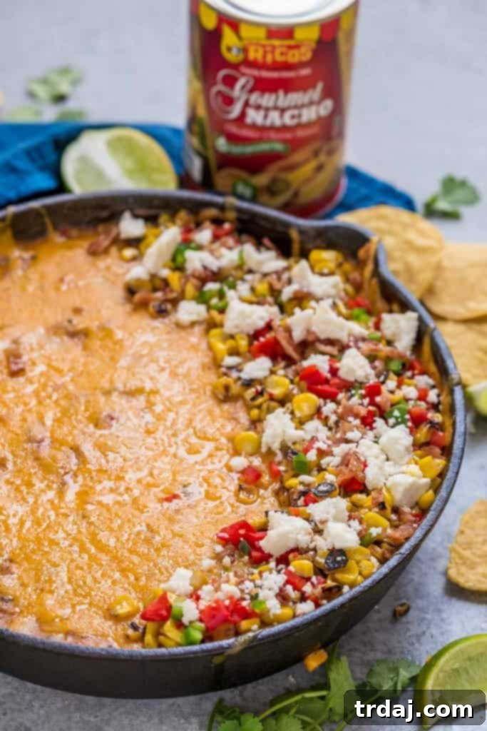 A vibrant bowl of Mexican Street Corn Queso, garnished with fresh cilantro and served with a side of tortilla chips.