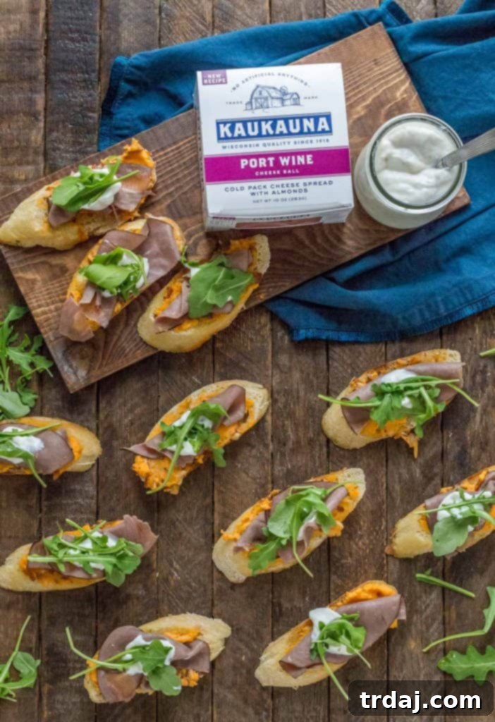 Delicious Roast Beef Crostini with Kaukauna Port Wine Cheese Ball, horseradish cream, and arugula, perfect for appetizers