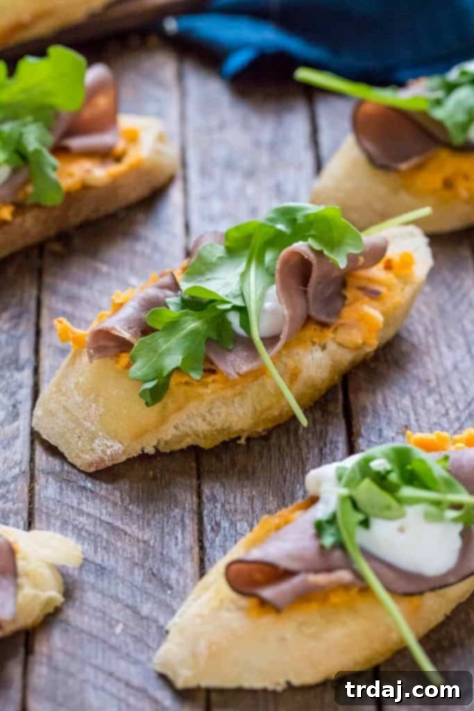 Close-up of Roast Beef Crostini showcasing the creamy Kaukauna cheese, savory roast beef, and fresh arugula