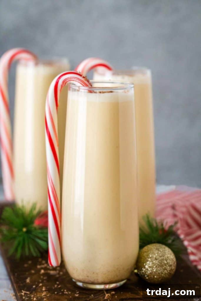 Chocolate Peppermint Eggnog Cocktail in a glass with a candy cane garnish and festive background.