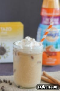 A glass of Pumpkin Pie Spice Chai Tea Latte with whipped cream.