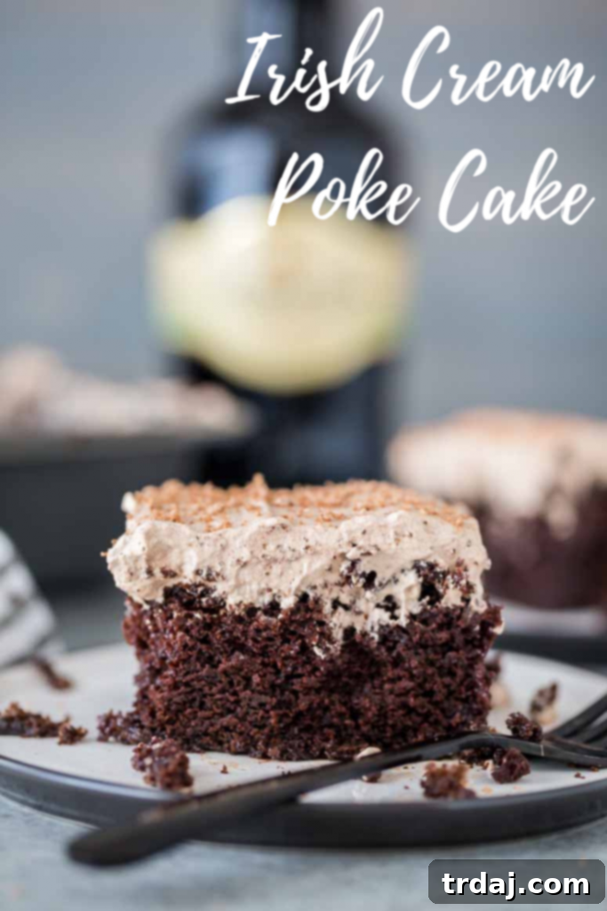 Homemade chocolate cake is soaked with Irish cream and topped with whipped cream frosting and a sprinkle of chocolate shavings for a decadent and creamy Irish Cream Poke Cake. A final stunning image of the Irish Cream Poke Cake, emphasizing its rich color and inviting texture