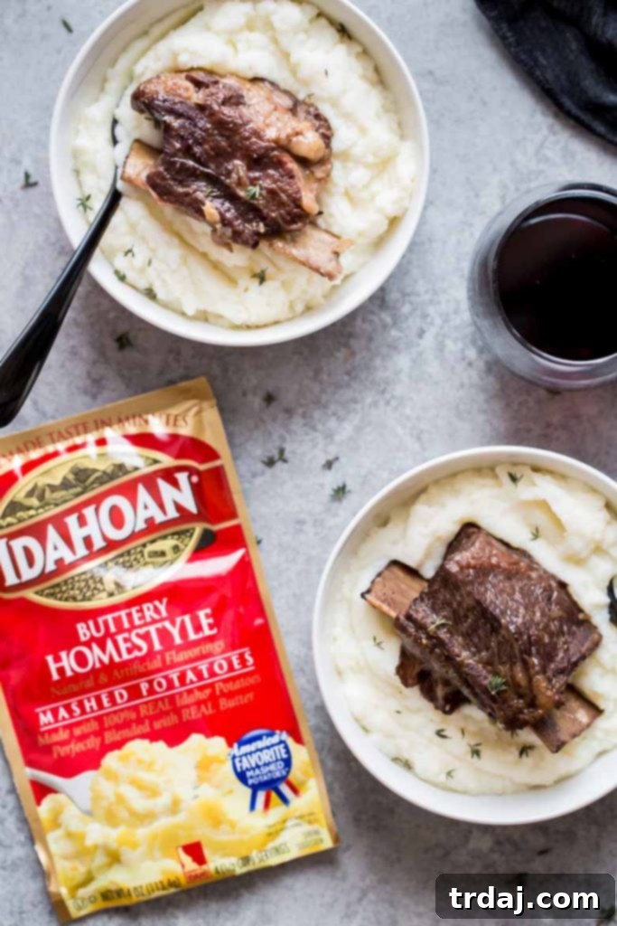 Tender Instant Pot Short Ribs served over creamy mashed potatoes, garnished with fresh herbs