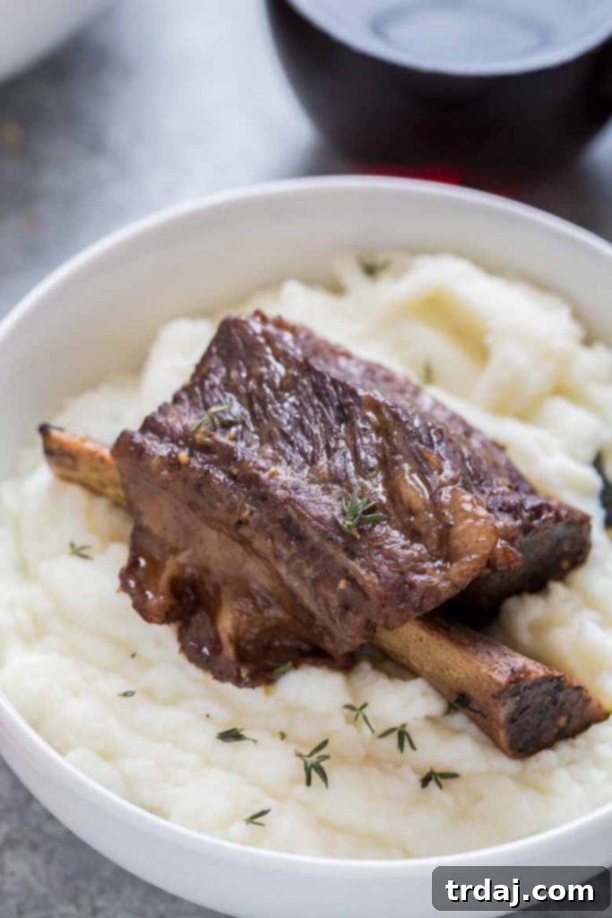 A delicious bowl of Instant Pot Short Ribs with mashed potatoes and fresh rosemary