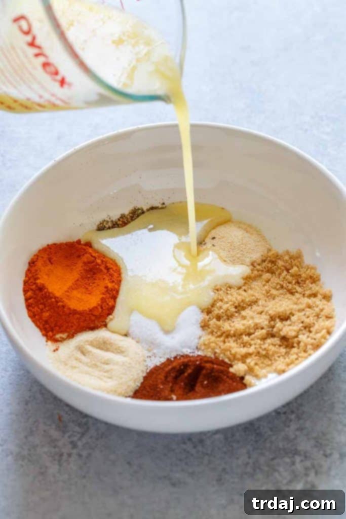 Nashville Hot Chicken Waffles Bites seasoning spices Melted butter being added to a bowl of Nashville Hot Chicken seasoning spices.