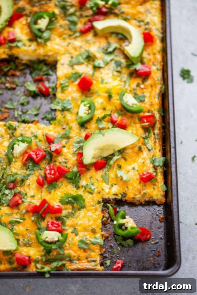 This Sheet Pan Mexican Frittata is packed full of delicious Mexican flavors and is perfect for a crowd or meal prep! A freshly baked Sheet Pan Mexican Frittata, golden brown and ready to be sliced, showcasing the hearty ingredients