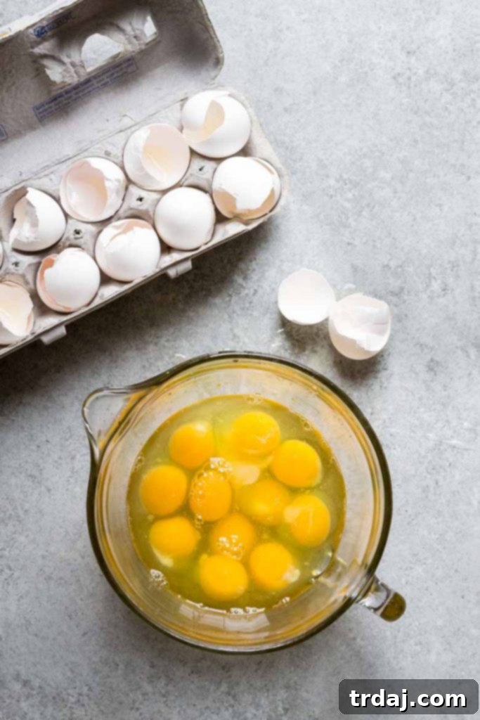 This Sheet Pan Mexican Frittata is packed full of delicious Mexican flavors and is perfect for a crowd or meal prep! Eighteen fresh eggs in a bowl, ready to be whisked for the sheet pan frittata, next to a 15x10 inch sheet pan