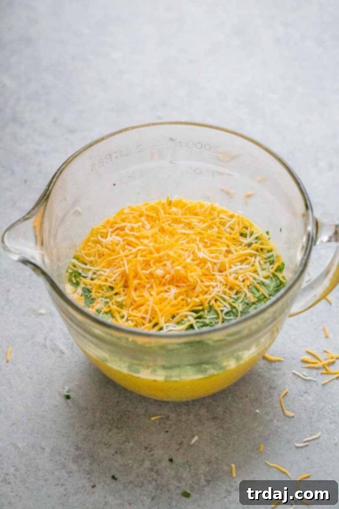 This Sheet Pan Mexican Frittata is packed full of delicious Mexican flavors and is perfect for a crowd or meal prep! Large bowl with whisked eggs, cilantro, and Cabot 4 Cheese Mexican Blend, ready to be poured