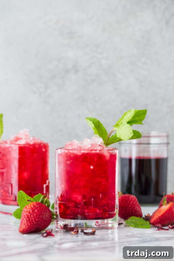Strawberry Hibiscus Mint Julep Bright red strawberry cocktail infused with hibiscus tea in a glass garnished with mint, with a focus on the vibrant color and refreshing appearance.