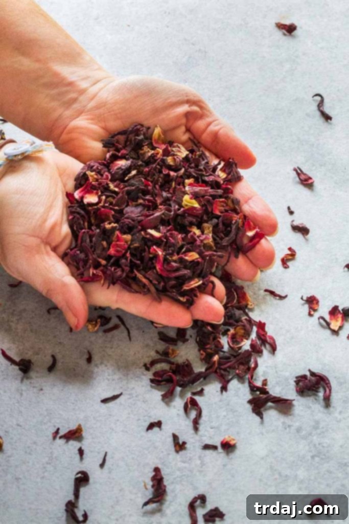 Strawberry Hibiscus Mint Julep Recipe Close-up of a Strawberry Hibiscus Mint Julep in a clear glass, showing the crushed ice, strawberry pieces, and mint garnish against a soft background.