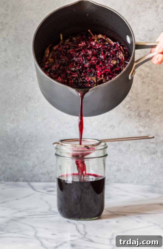Hibiscus Mint Simple Syrup Ingredients Ingredients for Strawberry Hibiscus Mint Julep simple syrup, including dried hibiscus flowers, sugar, and fresh mint, laid out on a clean surface.