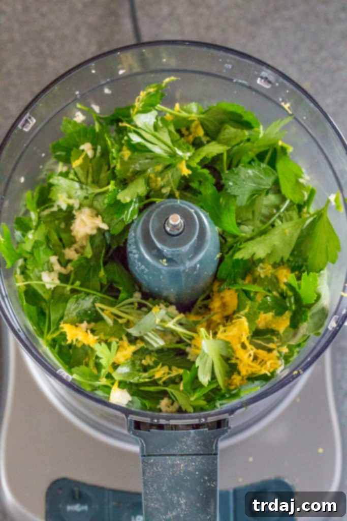 Preparing the vibrant green salsa verde by blending fresh herbs and olive oil.