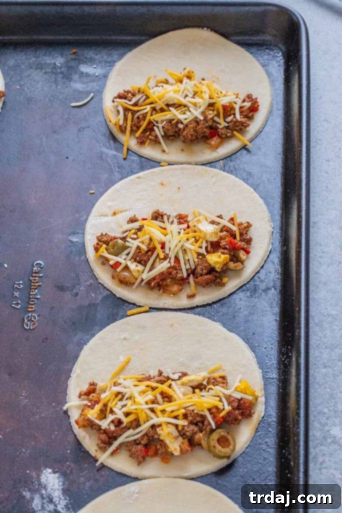 Place 1-2 tablespoons of empanada filling onto one side of the dough.  Top with cheese.