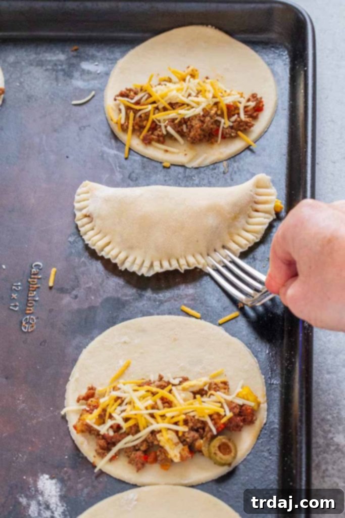 Using the tines of a fork, crimp edges all around empanada filling to close the pocket