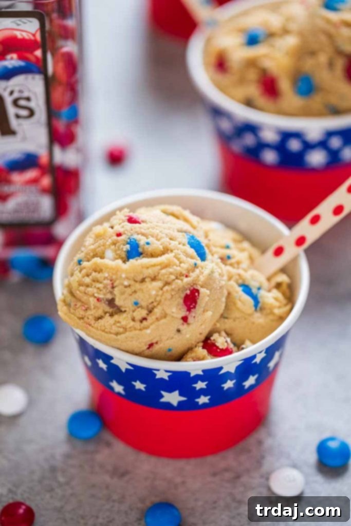A cup full of Patriotic Edible Cookie Dough, richly textured with colorful M&M's and sprinkles, showcasing a delightful no-bake dessert.