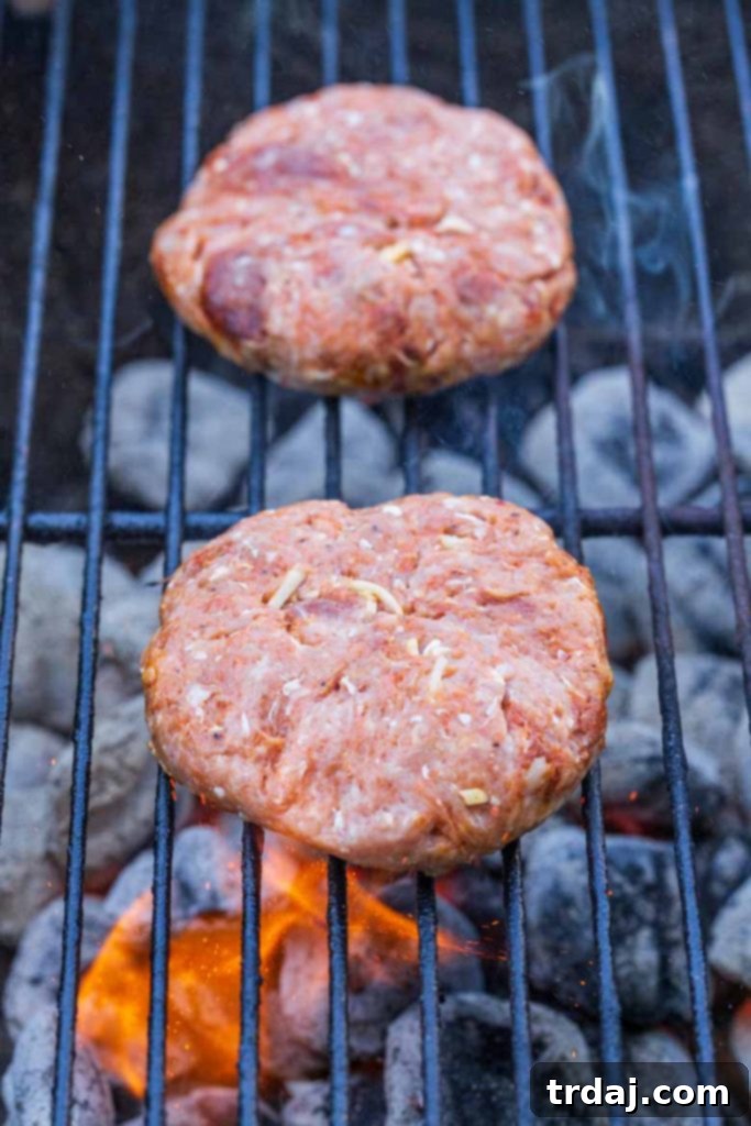 Chile Chorizo Burgers grilling on a charcoal grill, showing a slight char