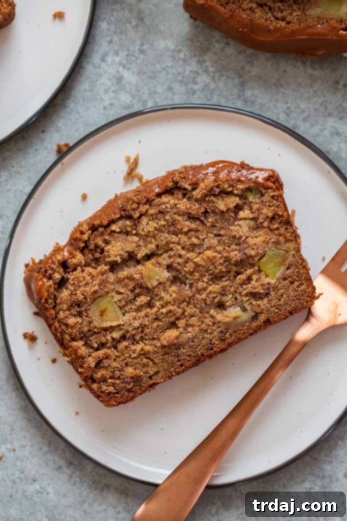 A slice of Caramel Apple Cider Banana Bread on a white plate, showing its moist interior.