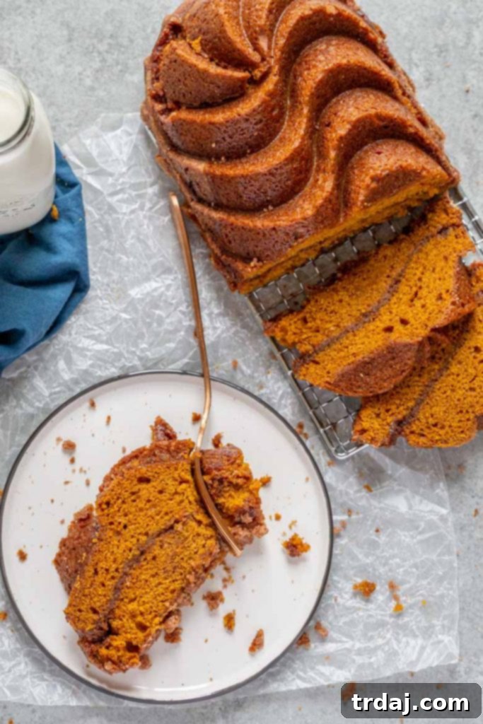A perfectly baked Snickerdoodle Pumpkin Bread loaf, golden brown and glistening with cinnamon sugar on top, ready to be sliced.