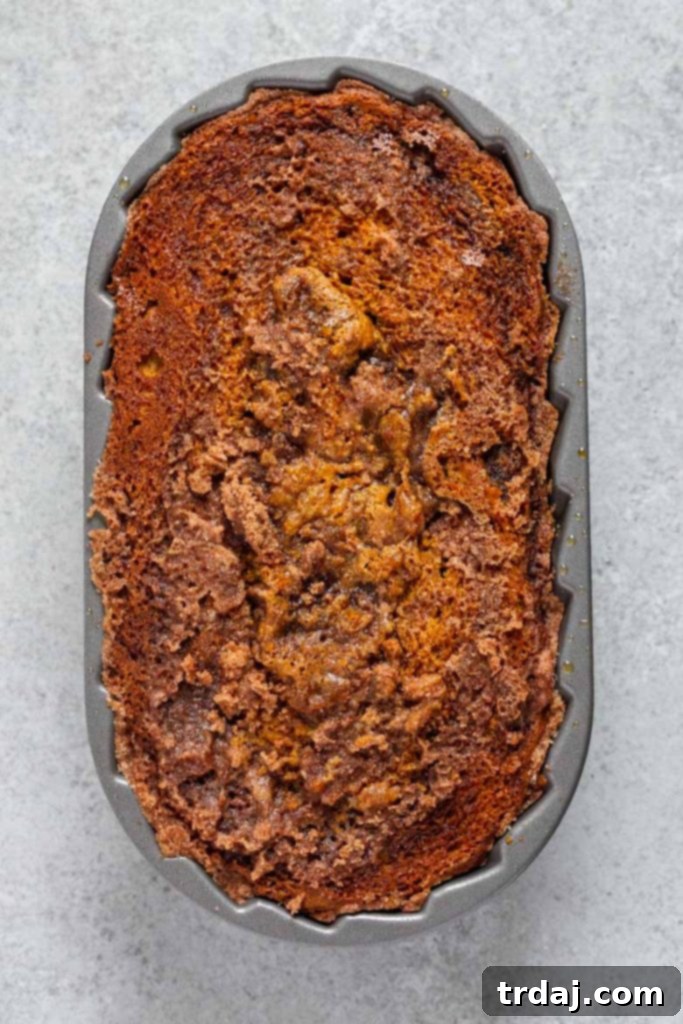 A whole Snickerdoodle Pumpkin Bread loaf resting on a cutting board, steam gently rising, promising a delightful treat.