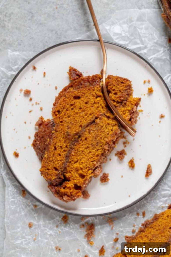 A thick slice of Snickerdoodle Pumpkin Bread on a white plate, revealing the internal ribbon of cinnamon sugar and moist texture.