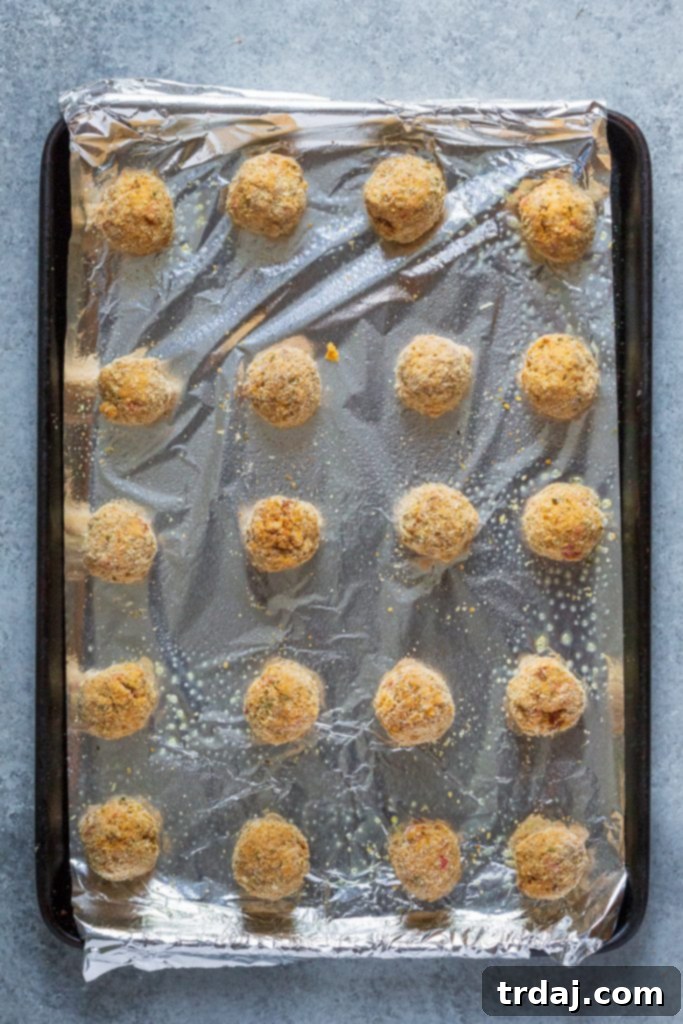 Freshly baked Pumpkin Sausage Cheese Balls cooling on a sheet pan, perfectly golden brown.