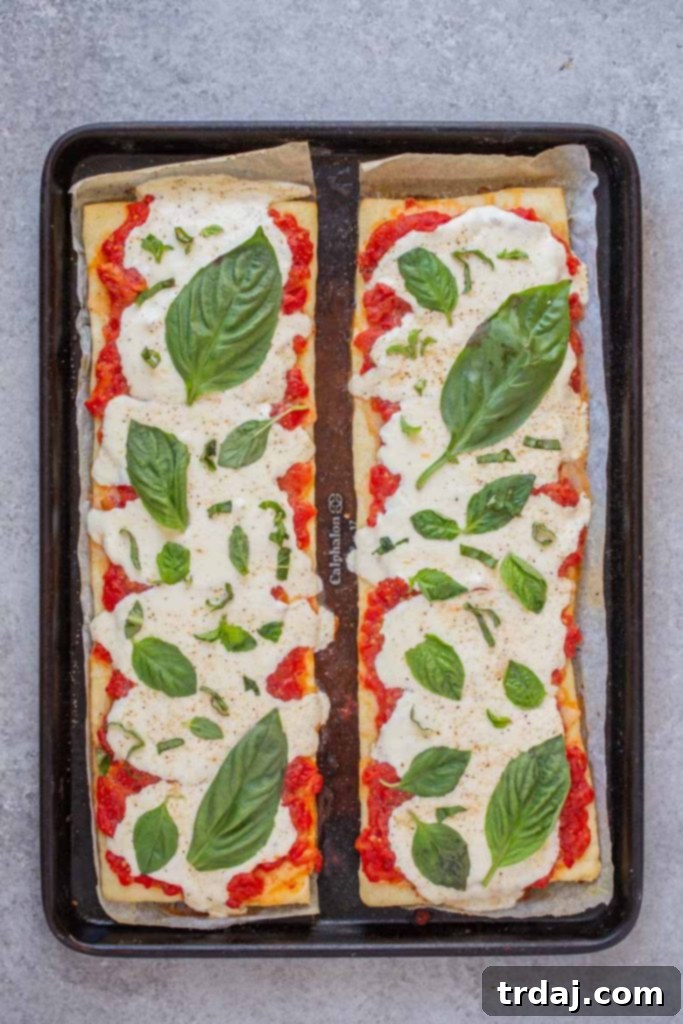 Top margherita flatbread with fresh basil leaves