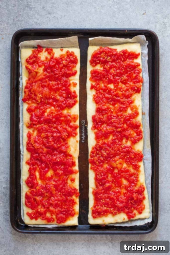 Place crushed tomatoes on top of cooked pizza crust