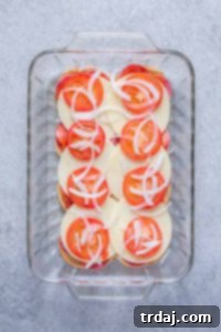 A generous layer of shredded iceberg lettuce being added as the final fresh component to the slider.